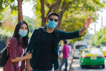 Couple travelers are holding hands together waiting for taxi car in the city street.