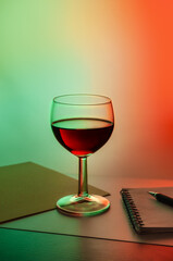 a glass of red wine on a background with red green lighting