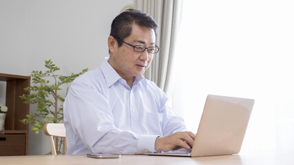 家でテレワークする中高年のビジネスマン