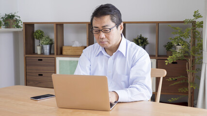 家でテレワークする中高年のビジネスマン