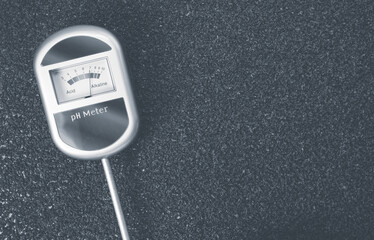 Top view closeup of an analog tool to measure the ph of the soil on a toned rough stone surface