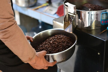 Close up professional coffee roaster holding bowl with beans. Control concept