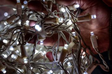 Fototapeta na wymiar hand gripping tangled christmas lights