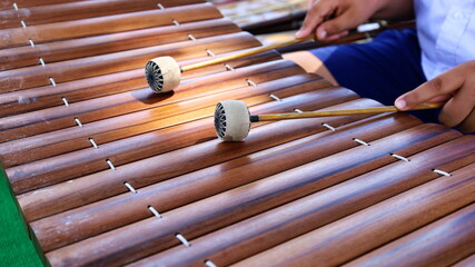 Male hand holding a xylophone stick. A boy student sitting on a xylophone instrument made of...