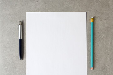 Template of white paper with a ballpoint pen and simple pencil on light grey concrete background....
