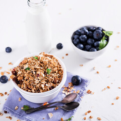 Muesli with blueberris in a bowl   on white wooden background. Delicious and healthy breakfast.