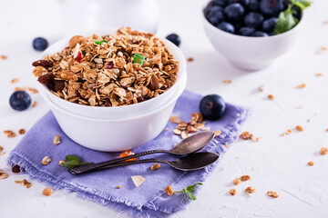Muesli with blueberris in a bowl   on white wooden background. Delicious and healthy breakfast.