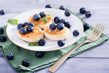 Cottage cheese pancakes, syrniki on white plate with  fresh blueberries. Healthy and delicious morning breakfast.Top view, copy space.