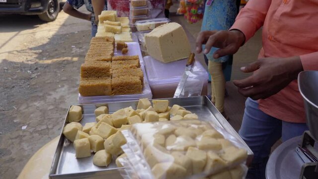 Kandi pedha street food sweet shopkeeper cutting in cubes Lonavala Karla mountain India