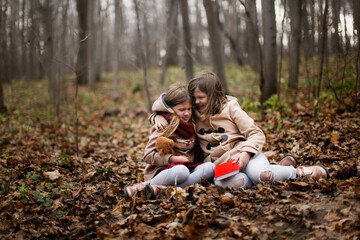 Caucasian children sisters hugs in park read a book on a picnic, children in the forest sit with a book in a meadow, autumn walks in warm coats