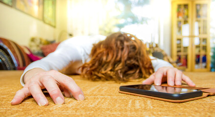A woman has health problems and is lying in a room. Next to her hand is a phone.