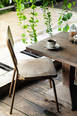 Selective focus of Cup of coffee on old wooden table with vintage wood and metal school chair in coffee shop.
