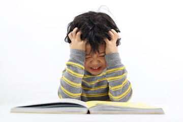 Little Asian boy frustrated over homework with his both hand on his head. Boy studying at table isolated on white background.