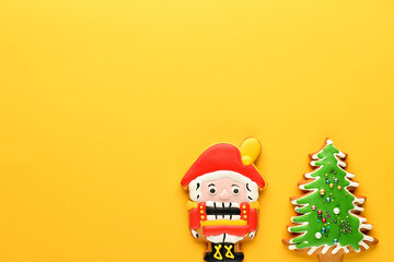 Nutcracker and Christmas tree ginger biscuit on a yellow background. New year and Christmas background. Flat lay