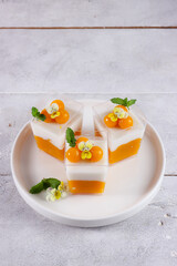 Puding mangga or Homemade fresh mango jelly and coconut pudding decorated with mint and viola edible flowers.