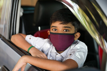 Portrait of young Indian boy wearing protective mask while traveling by a car