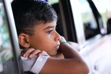 Portrait of young Indian boy watching out white traveling by car