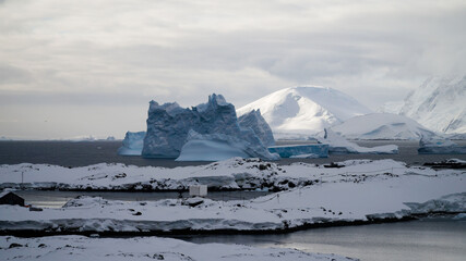 Icebergs and snow capped mountains in the Antarctic Peninsula after passing the Lemaire Channel in...