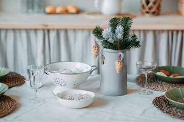 Christmas decorations. Fir branches with snow inside the vase on the christmas table. Decoration of festive table for christmas eve. Festive dish for new year eve.