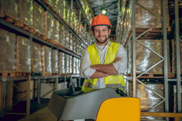 Warehouse worker in orange helmet looking contented