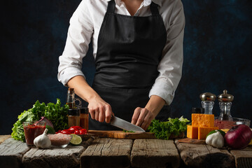 Chef cuts with knife greens on wooden chopped board. Backstage of preparing dinner at restaurant...