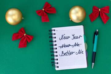 Writing in a notebook New Year - better me on green background with Christmas balls and bows. New...