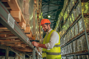 Warehouse worker in yellow vest checking boxes on the shelves
