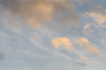 Colorful blue sky and clouds highlighted by setting sun, as a nature background
