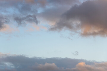 Colorful blue sky and clouds highlighted by setting sun, as a nature background
