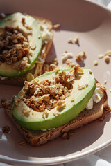 Healthy avocado toasts for breakfast or lunch with rye bread, sliced avocado, baked granola with nuts. Vegetarian food. Plant-based diet. Clean eating. Top view.