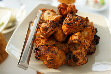 A plate of Tandoori Chicken. Tandoori chicken is a chicken dish prepared by roasting chicken marinated in yogurt and spices in a tandoor, a cylindrical clay oven.