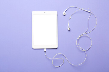 Fototapeta na wymiar Tablet computer with earphones on color background