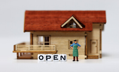 Close-up on a 'OPEN' and a miniature man. Concepts about shops that are starting to reopen.
