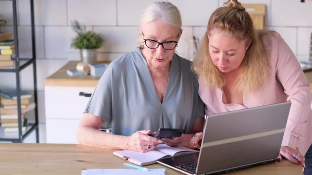 Woman teaching senior mother to use internet at home. Senior woman with her daughter looking at modern gadget indoors. close up view. Slow motion nvideo. stock footage