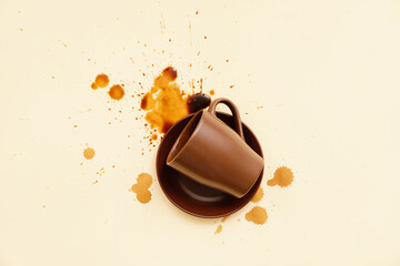 Overturned cup and spilled coffee on color background