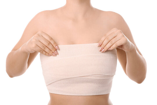 Woman with bandage on her chest against white background. Breast augmentation concept