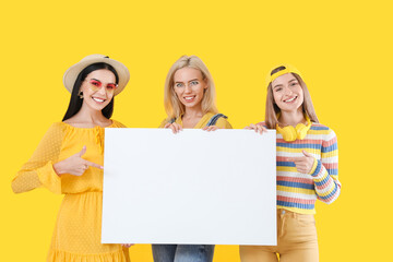 Beautiful young women with blank poster on color background