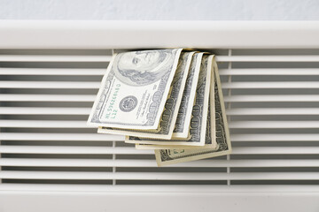 Radiator with dollar banknotes, closeup. Concept of heating season