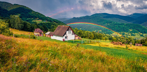 Huge ainbow at the summer rain. Panoramic morning view of Kvasy village, Transcarpathian, Ukraine....