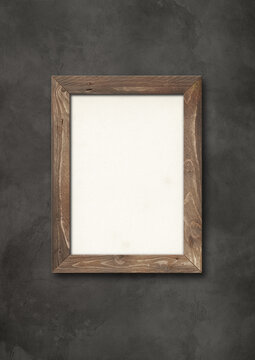 Old brown rustic wooden picture frame hanging on a concrete wall