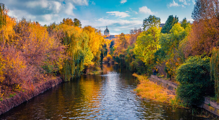 Sunny autumn view of Seret river in Ternopil city park with Church of Saints Volodymyr and Olha on background. Picturesque morning cityscape of Ternopil town, West Ukraine, Europe.