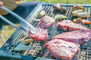 屋外のオープングリルで牛肉を網焼きしている様子