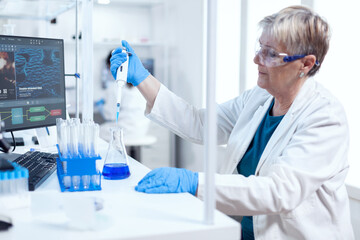 Senior chemist woman using molecular dropper during healthcare experiment. People in innovative pharmaceutical laboratory with modern medical equipment for genetics research.