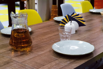 Table appointments in a childrens playground cafe. Empty plates and carafe of juice Napkin on a...