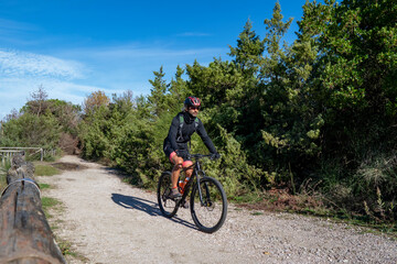 Naklejka premium A biker on the traks of San Rossore and Massaciuccoli Natural Park, Tuscany