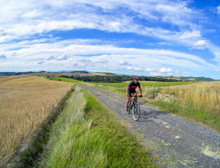 A biker on a classic white road of Tuscany