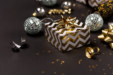 Christmas festive holiday card. Gold and silver decorations, mirror disco balls, gifts on dark black background.