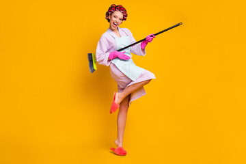 Full length body size view of overjoyed cheerful maid jumping playing broom isolated bright yellow color background