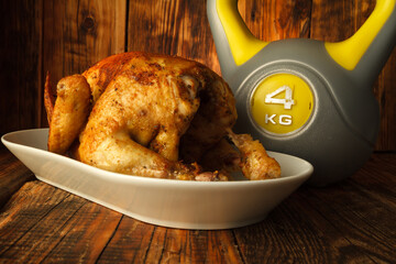 Roasted homemade chicken for Thanksgiving dinner and heavy kettlebell. Autumn composition on wooden...