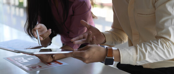 UI developer team consulting on their project with tablet and paperwork